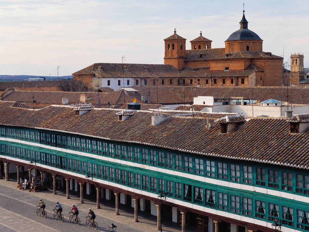 Ciclistas cruzando la Plaza Mayor de Almagro, bajo sus galerías acristaladas de color verde