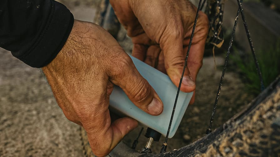 Manos de mecánico revisando la rueda de una bicicleta gravel durante la ruta